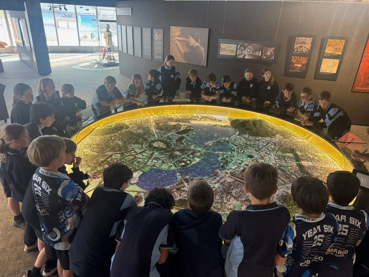 Students grouped around a large round table on whick is a map of the city of Canberra.