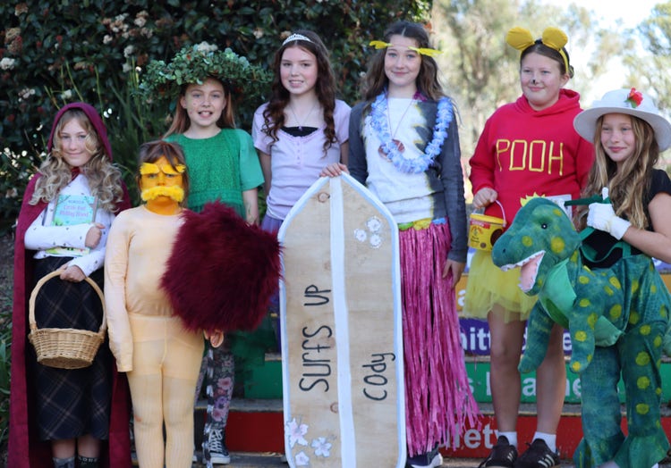 Group of students in various book character costumes, including the Lorax, little red riding hook, winnie the pooh and Dorothy the Dinosaur.