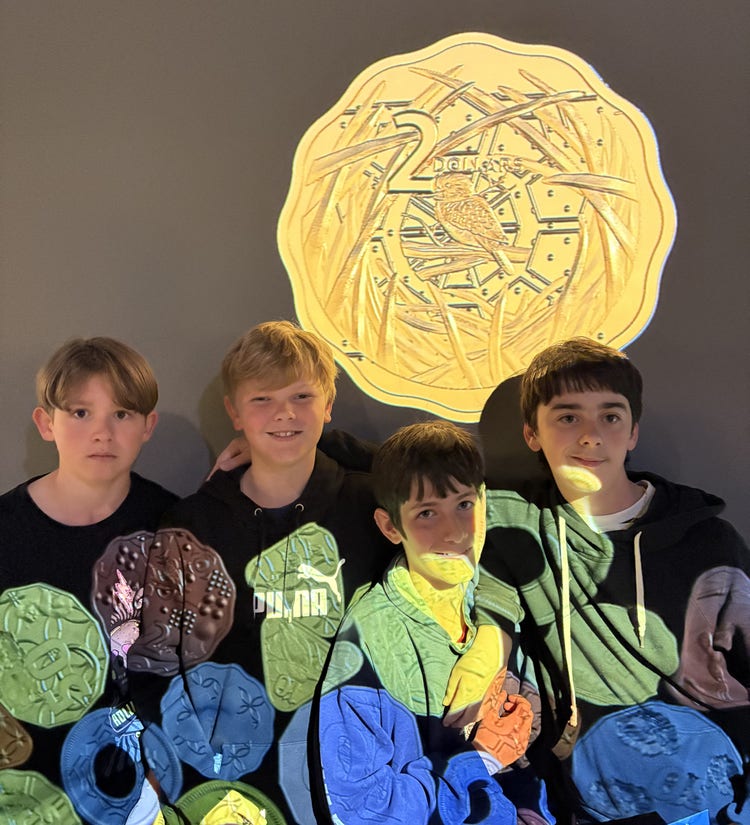 A group of students standing against a wall with projections of coins across their persons and on the wall behind them.
