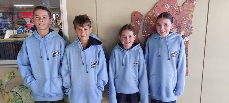 Four students proudly wearing their zone cross country representative hoodies.