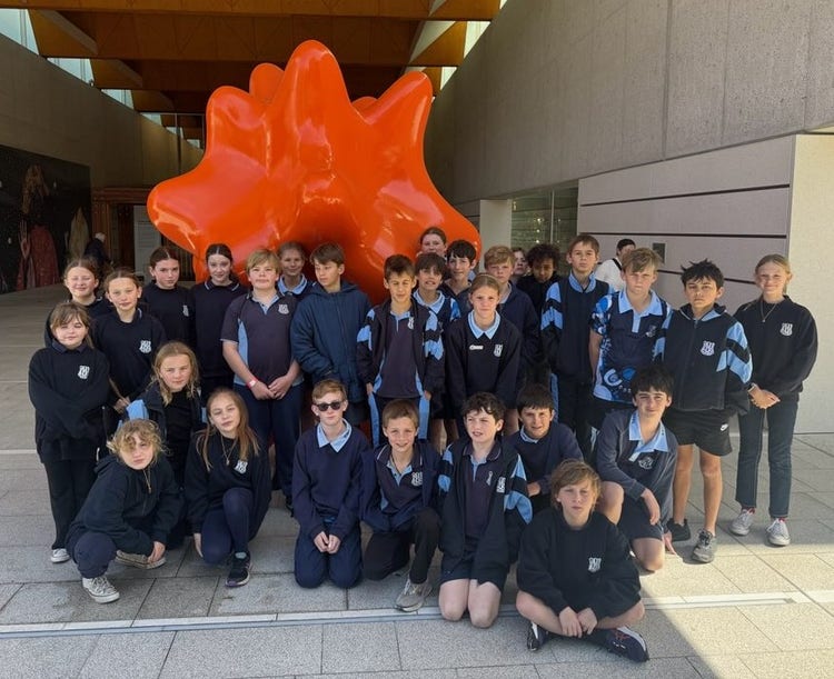 Students gathered at the entrance of the National Portrait Galleries large orance sculpture.
