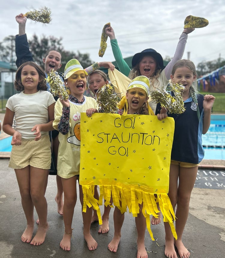 Cheer squad at the swimming pool with streamers and a large yellow sign - GO! STAUNTON GO!