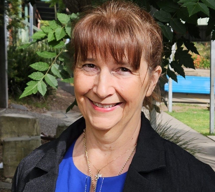 Gillian Park - Principal of Cobargo Public School standing in the playground in front of the foliage of a tree.
