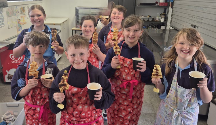 Students happily holding up the pastry christmas trees and a cup of lemonade.