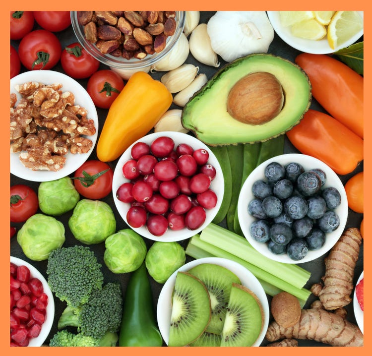 Collection of healthy fruits, nuts and vegetables arranged - some in bowls and some spaced across to form a colourful display.