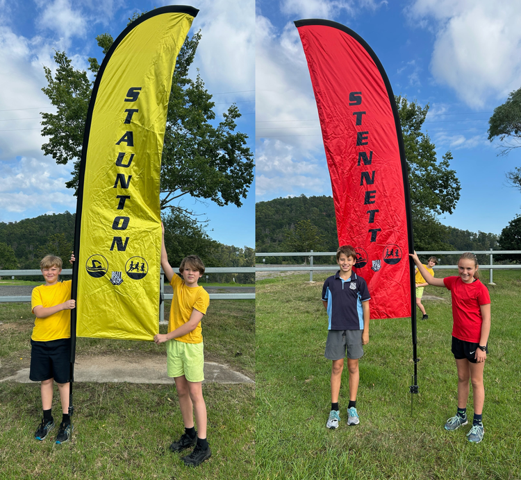 Students standing next to Staunton and Stennett House flags in the house colours of yellow and red.